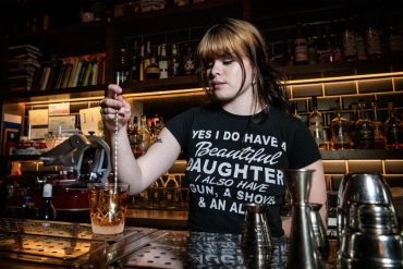 young female bartender mixing drink